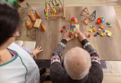 A caregiver in a memory care facility stimulating patient with dementia.