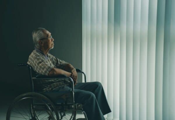 Lonely senior sitting in a wheelchair at home.