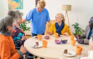 Caregiver and senior residents enjoying snack time in assisted living.