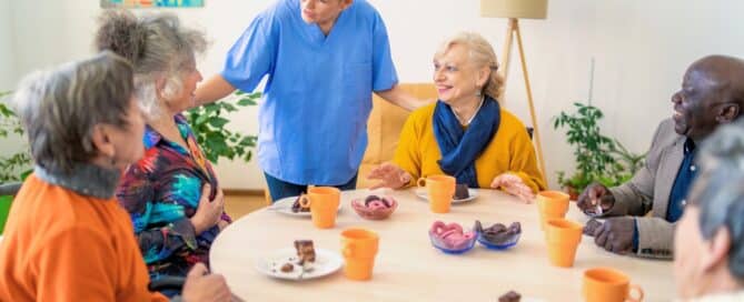 Caregiver and senior residents enjoying snack time in assisted living.