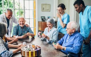 Groups of seniors in assisted living playing cards.