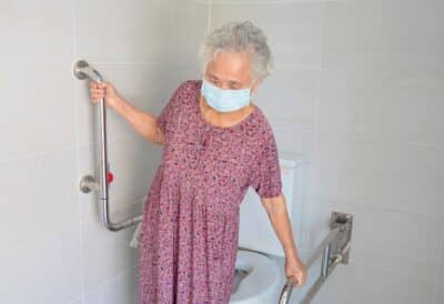 Female senior holding the bathroom grab bars.