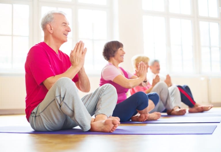 Group of seniors practicing yoga at an independent living community fitness centers.