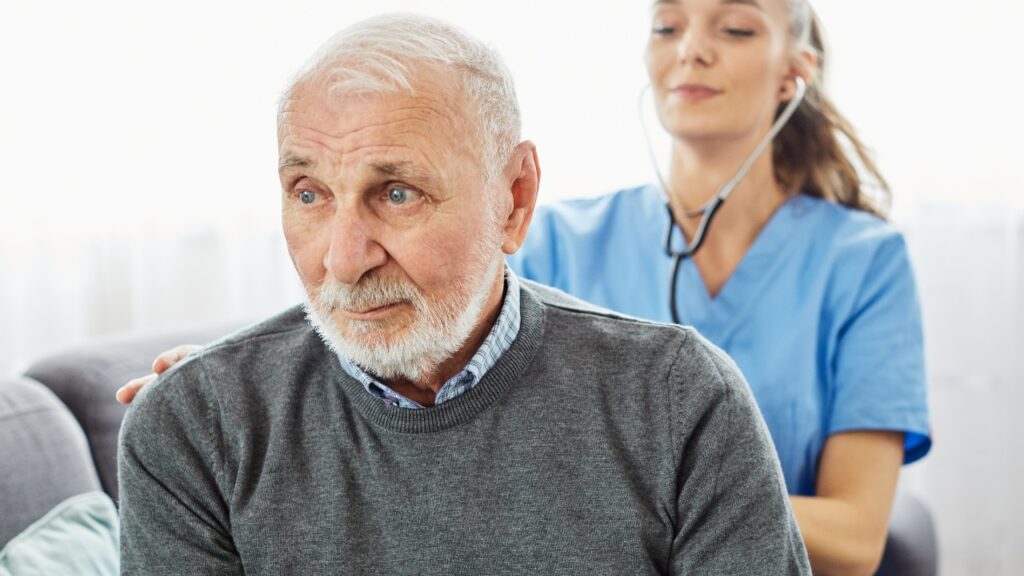 Caregiver checking up senior man during in-home care.