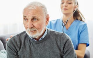 Caregiver checking up senior man during in-home care.