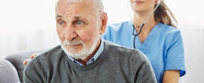 Caregiver checking up senior man during in-home care.