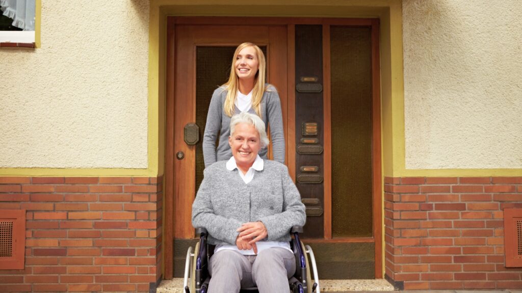 Caregiver and smiling senior woman in a wheelchair eligible for assisted living facility.