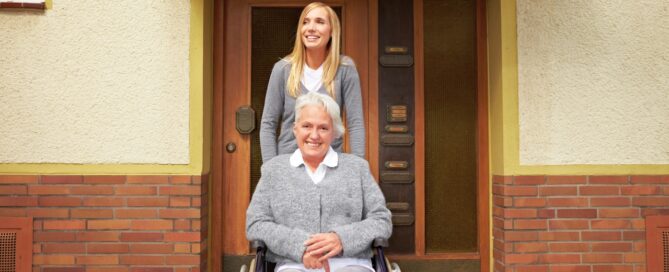 Caregiver and smiling senior woman in a wheelchair eligible for assisted living facility.