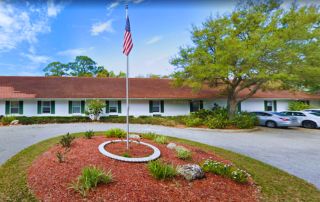 Family Extended Care of Sarasota (DBA) Cabot Reserve on the Green Outside Part with Flag Pole and US Flag, and parking space.