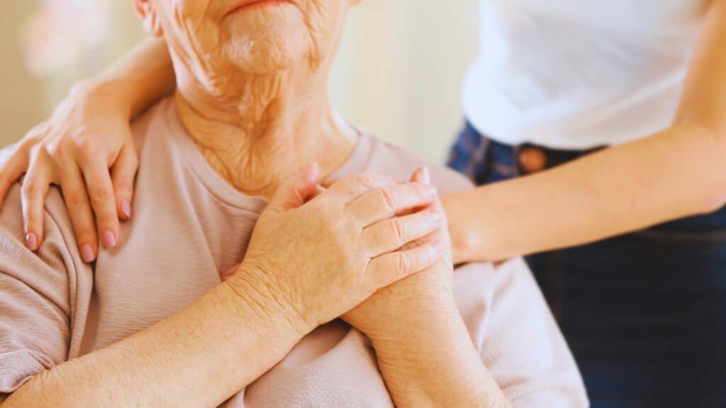 Senior woman in hospice care placing the hands of her caregiver above her heart.