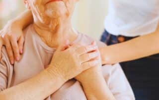 Senior woman in hospice care placing the hands of her caregiver above her heart.