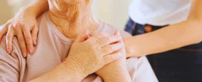 Senior woman in hospice care placing the hands of her caregiver above her heart.