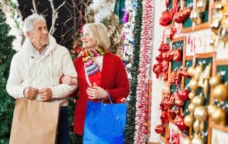 Senior couple, man and woman, holding each a giftbag, walking in a clear pathway as part of holiday safety tips.