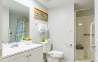 Grand Villa of Sarasota bathroom with a toilet, sink and shower stall, and grab bars.