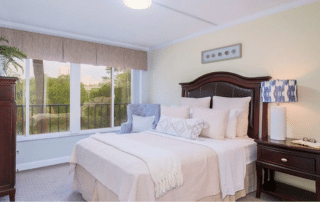 Grand Villa of Sarasota apartment bedroom with a bed, dresser and window.