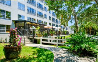 Grand Villa of Sarasota apartment building with a walkway and patio area.