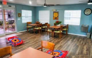 Heron East activities room with tables and chairs in front of a sliding glass door.