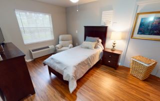 Heron East model bedroom with hardwood floors and a single bed.