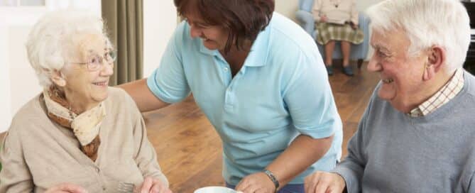 Senior couple eating assisted by caregiver when to move from independent to assisted living.
