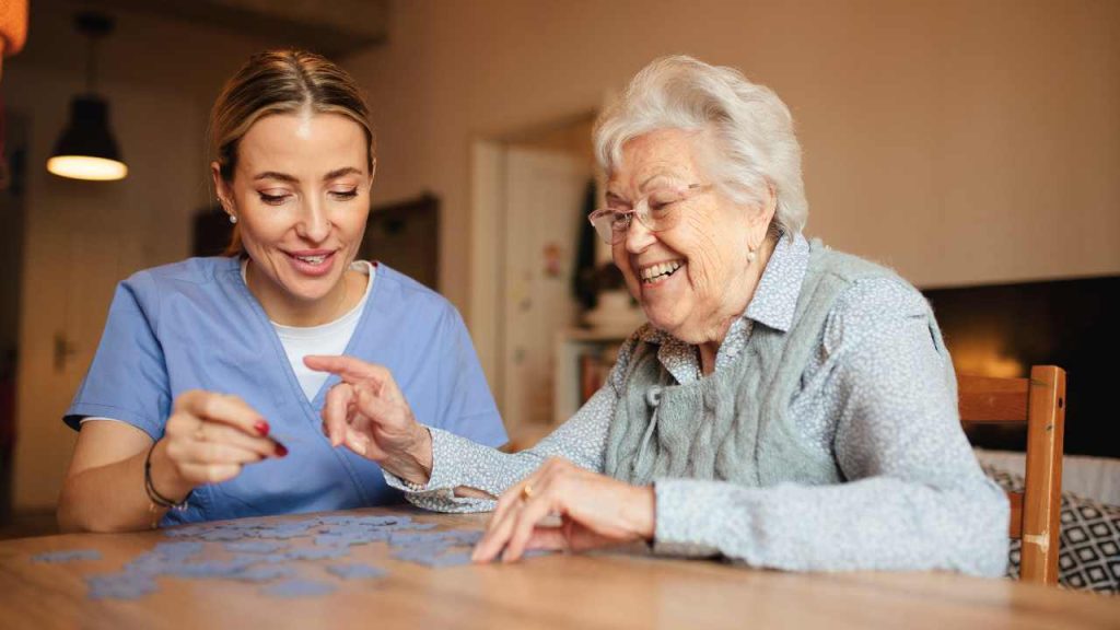 Companion caregiver playing puzzle with a senior.