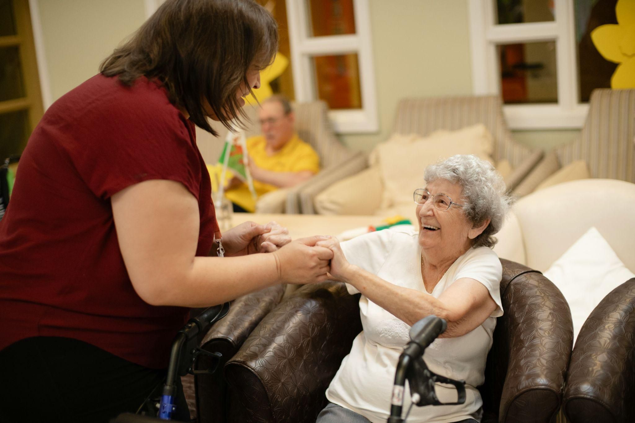 a caregiver helping an elderly woman stand.