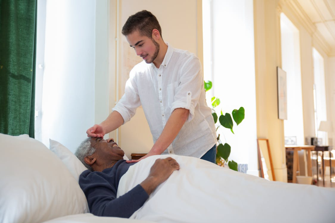 A person taking care of an elderly man.