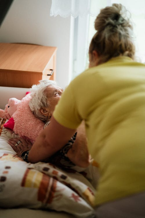A person putting a senior to bed.