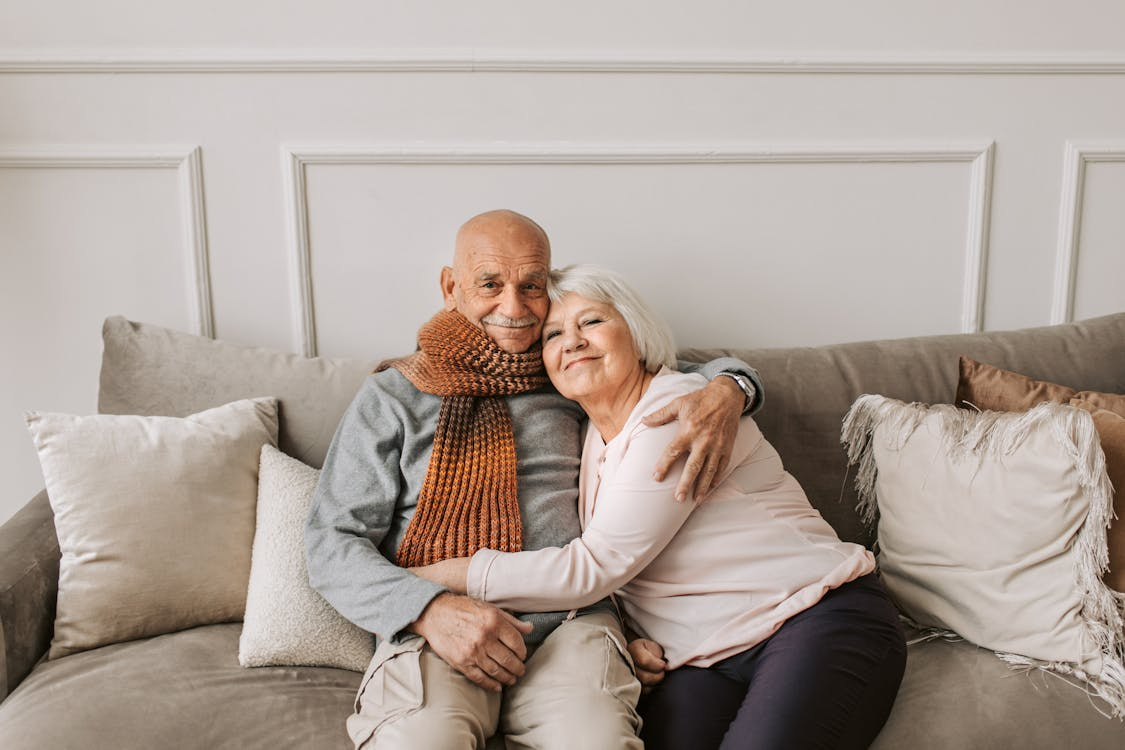  An elderly couple sitting on a couch.