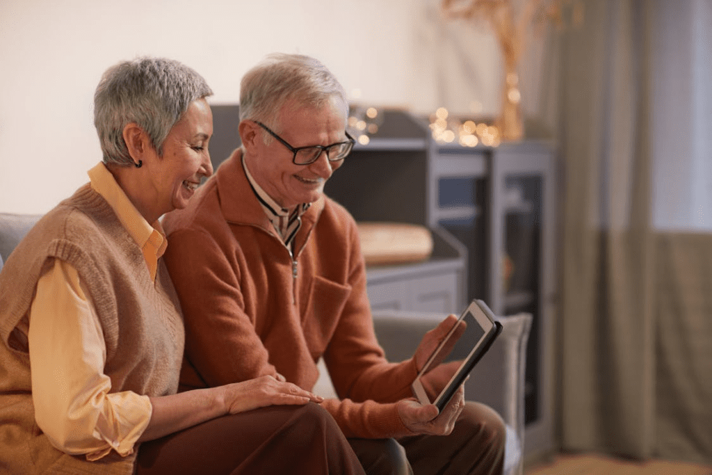 An elderly couple smiling at their tablet.