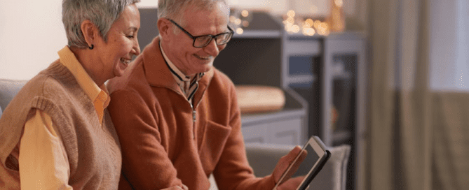 An elderly couple smiling at their tablet.