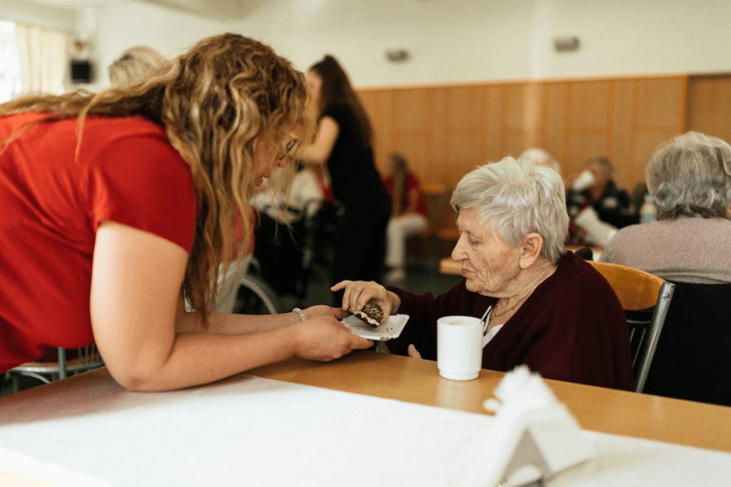 A person giving an elderly person a confectionery