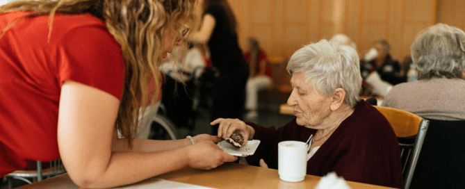 A person giving an elderly person a confectionery
