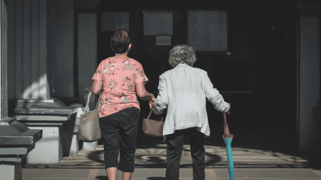 A person holding the hand of an elderly person on the street