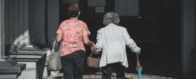 A person holding the hand of an elderly person on the street