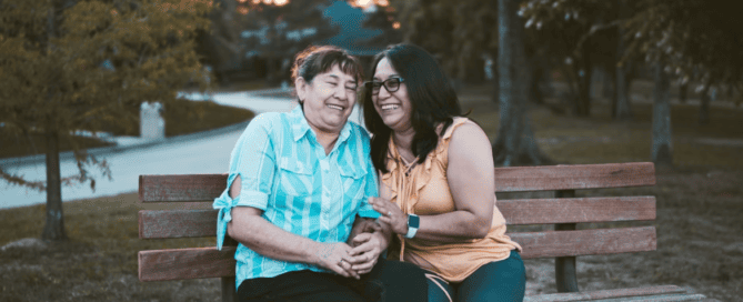 A person with their elderly parent on a bench