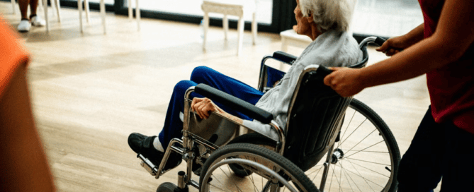 A caregiver pushing the wheelchair of an elderly person