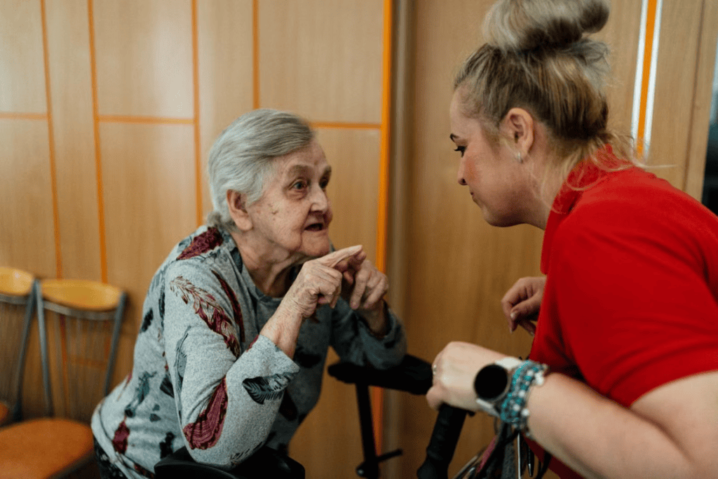 An elderly person talking to a caregiver
