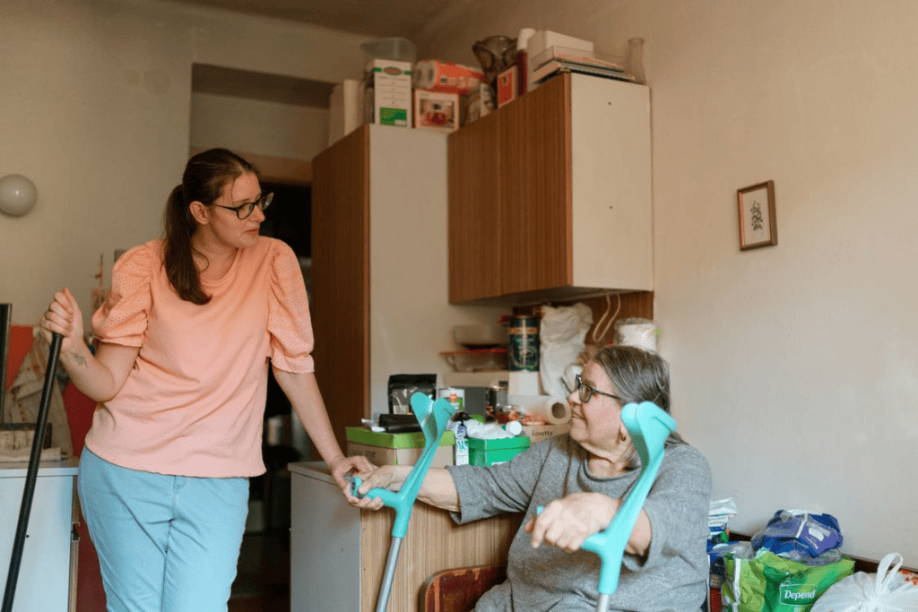 An elderly person holding walking sticks next to a caregiver
