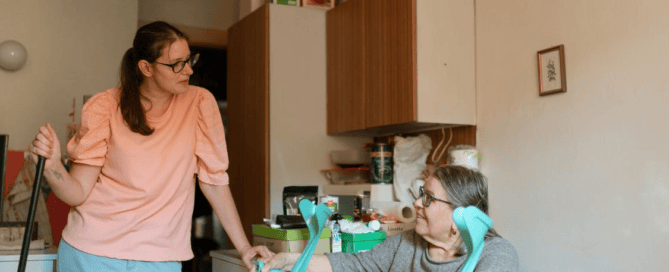 An elderly person holding walking sticks next to a caregiver