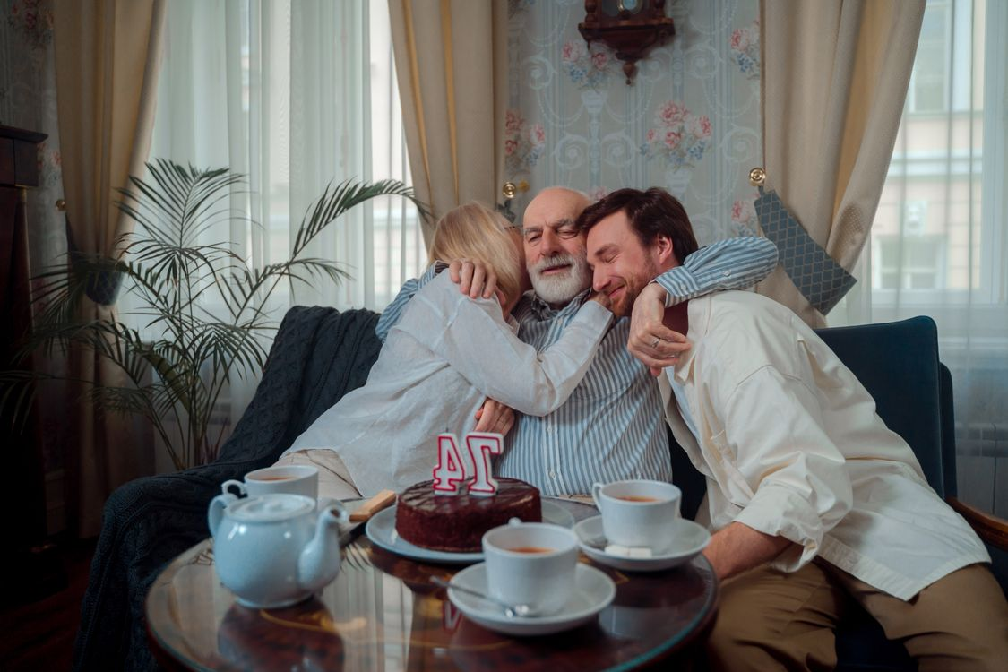 An elderly person hugging their children