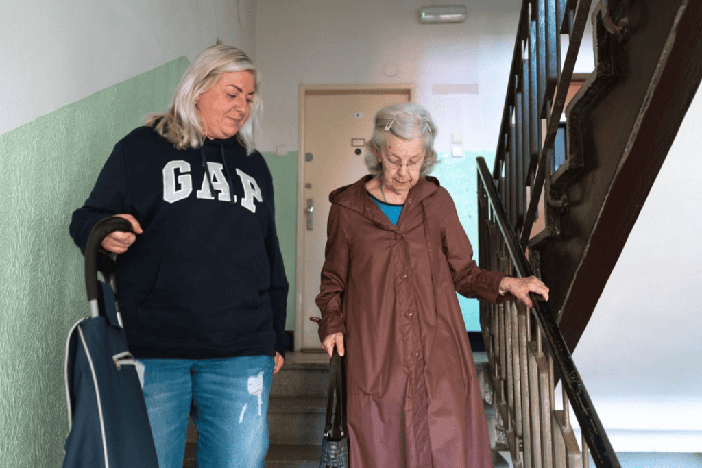 An elderly person and their caregiver climbing down the stairs