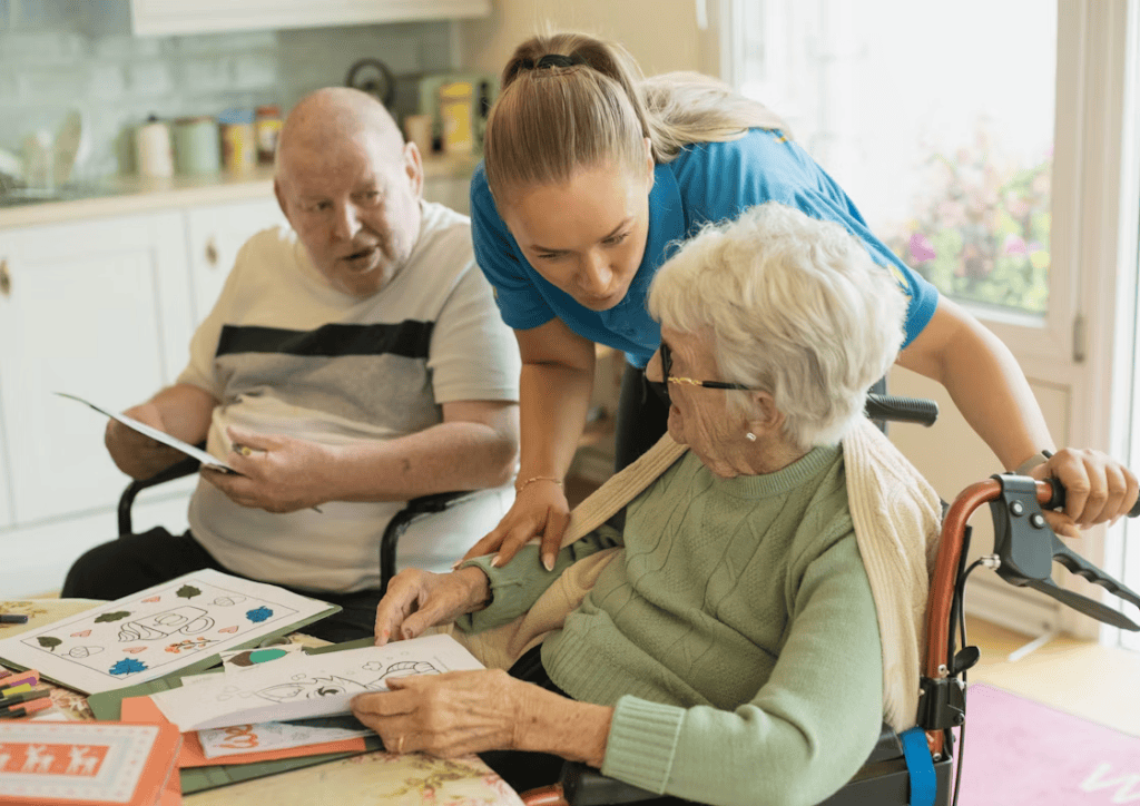 caregiver assisting an elderly couple with coloring
