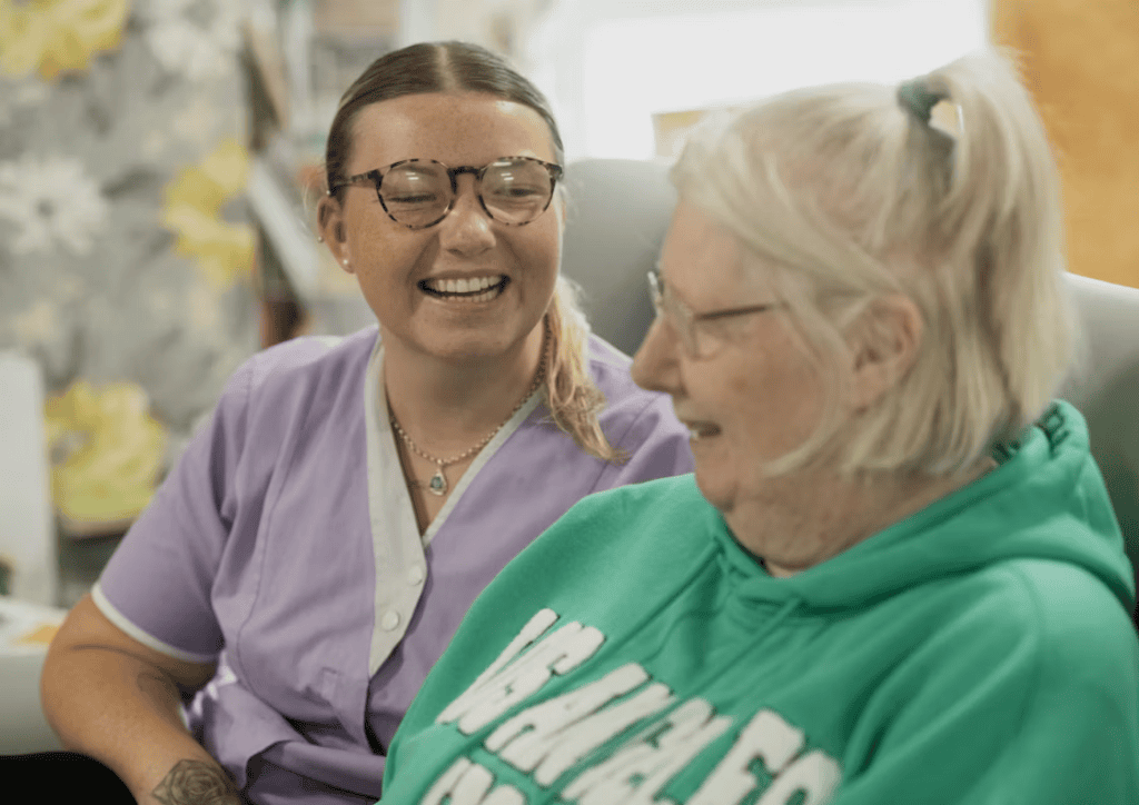 A person laughing with their elderly parent 