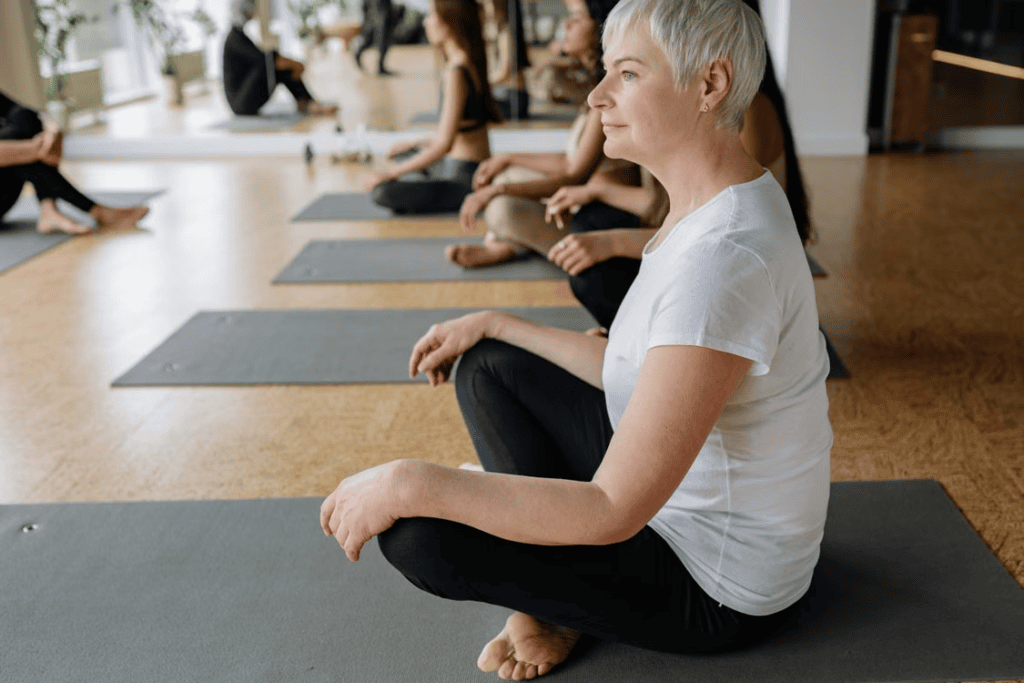 A senior sitting with their legs crossed on a yoga mat