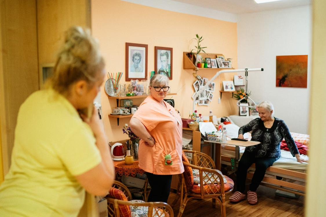 An elderly person in a nursing home with two caregivers