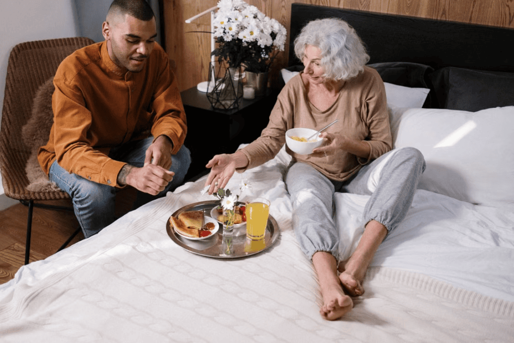 A caregiver serving food to an elderly person in bed