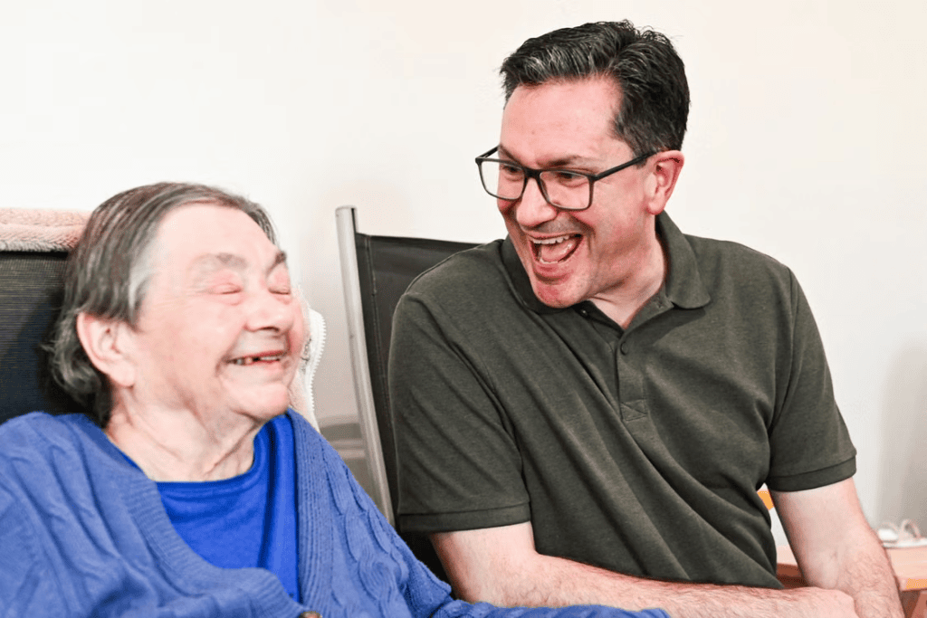 A caregiver and an elderly person smiling and talking