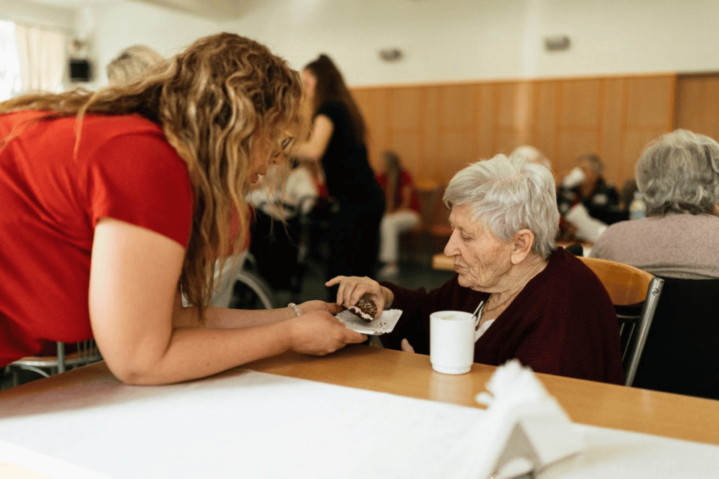 A caregiver serving food to an elderly person