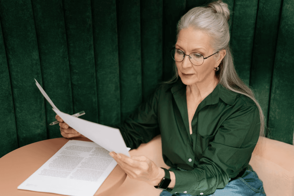A senior woman reviewing documents at a desk indoors