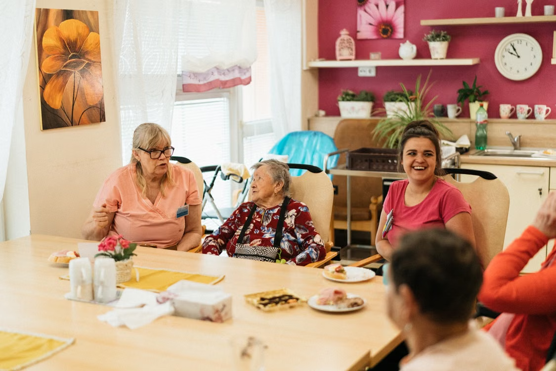 Elderly people and their caregivers around a table in a nursing home